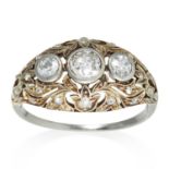 AN ART DECO DIAMOND RING in platinum or white gold, the trio of round cut diamonds, within scrolling