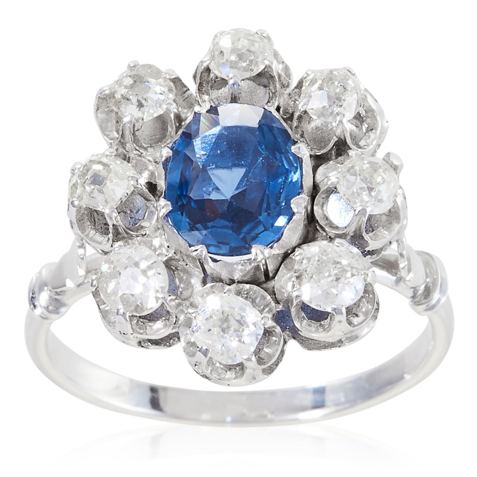 A SAPPHIRE AND DIAMOND CLUSTER RING in platinum or white gold, the oval cut sapphire encircled by