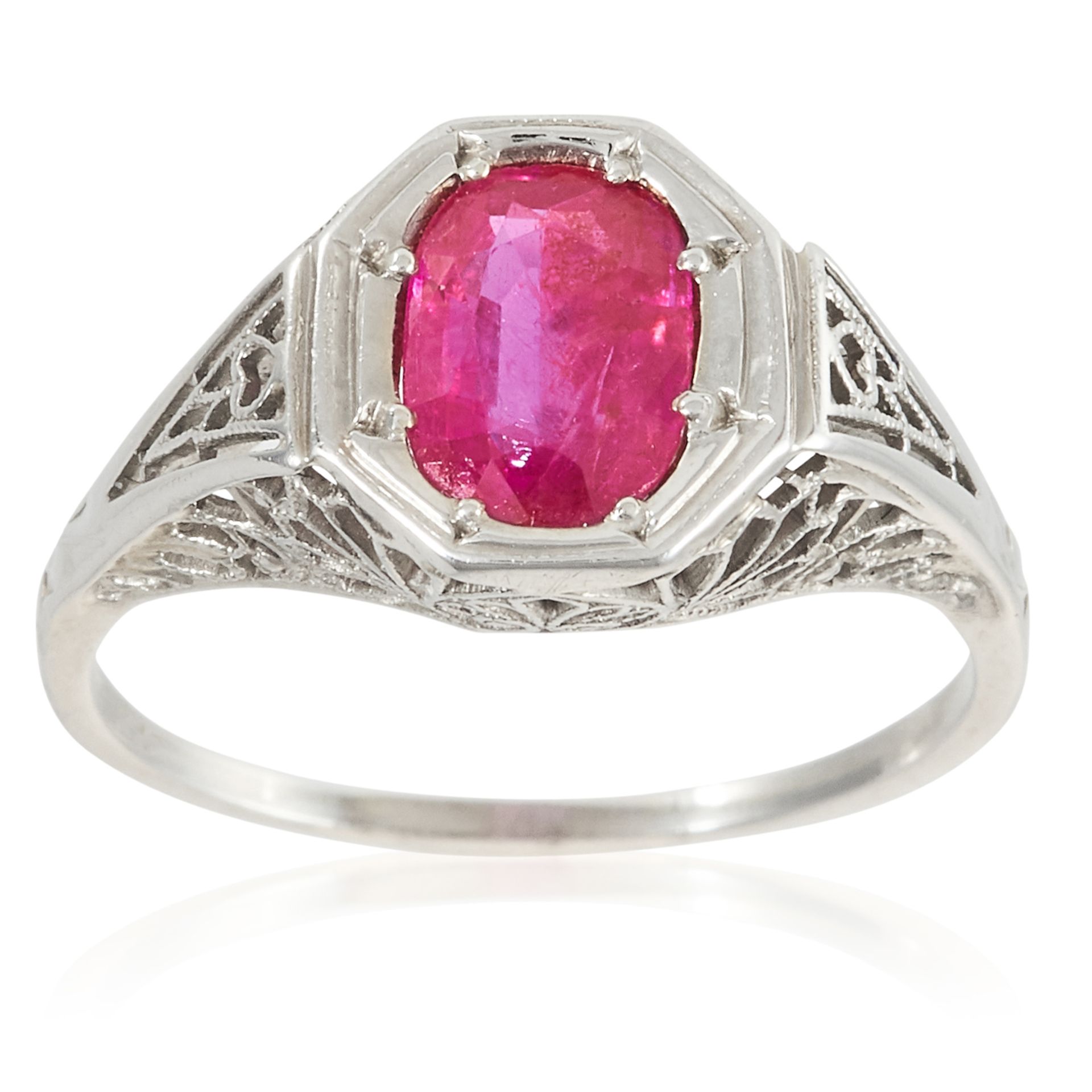 AN ART DECO RUBY DRESS RING in white gold, set with an oval cut ruby in open scrolling frame, marked