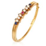 AN ANTIQUE RUBY, SAPPHIRE, PEARL AND DIAMOND BANGLE in high carat yellow gold, the undulating body