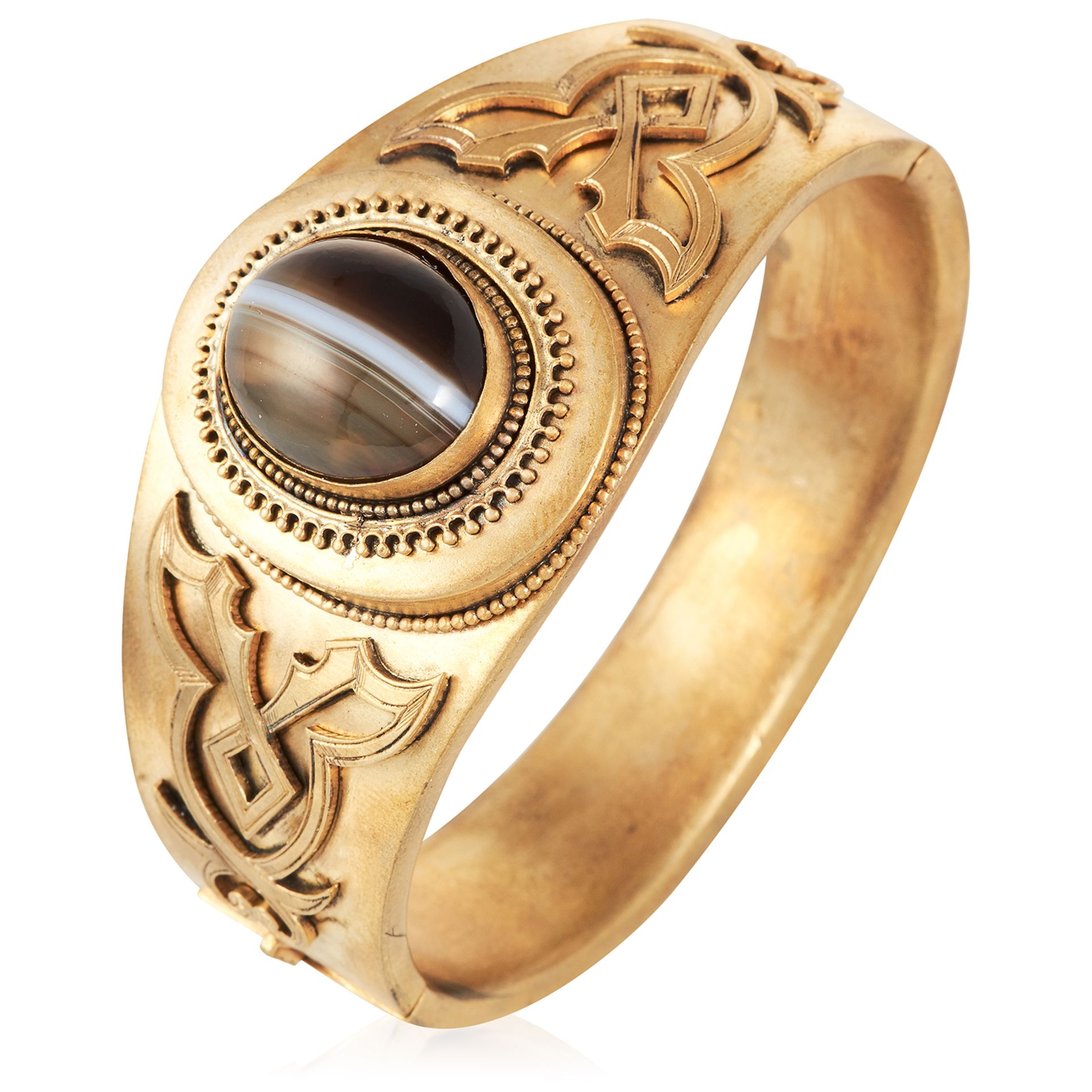 AN ANTIQUE BANDED AGATE BANGLE in yellow gold, set with a cabochon banded agate in scrolling design,