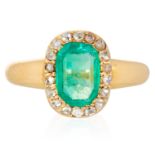 AN EMERALD AND DIAMOND CLUSTER RING in high carat yellow gold, set with an emerald cut emerald in