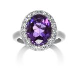 AN AMETHYST AND DIAMOND CLUSTER RING in white gold or platinum, set with an oval cut amethyst of