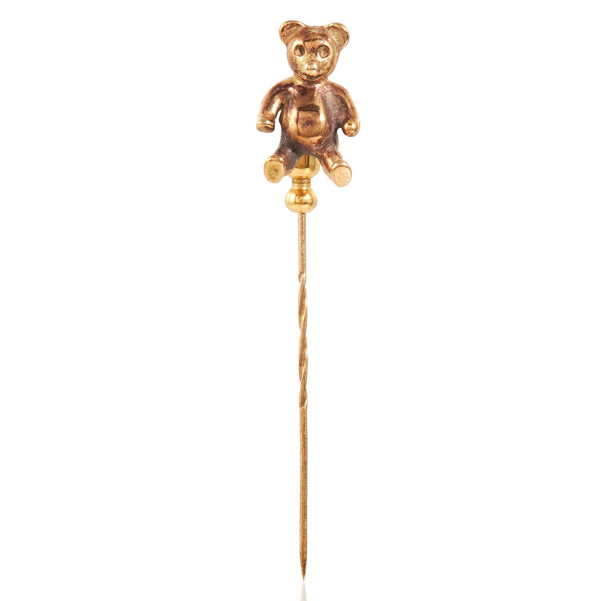 AN ANTIQUE TEDDY BEAR TIE / STICK PIN in yellow gold, the pin surmounted by a gold bear,