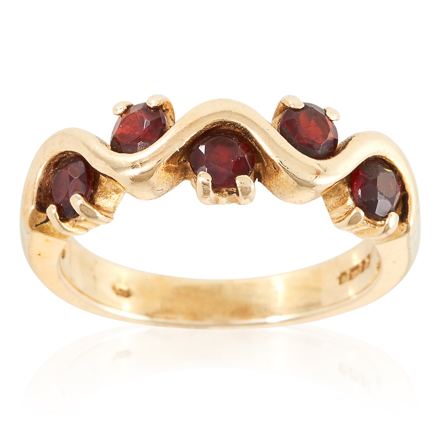 A GARNET DRESS RING in yellow gold, set with five round cut garnets in undulating form, British