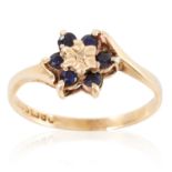 A SAPPHIRE AND DIAMOND CLUSTER RING in yellow gold, set with a round cut diamond in a cluster of