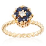 A SAPPHIRE AND DIAMOND CLUSTER RING in yellow gold, set with a round cut diamond and six round cut