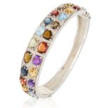 A GEM SET BANGLE in sterling silver, set with various gems include garnet, amethyst, citrine, topaz,