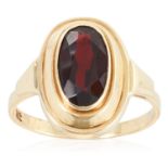 A GARNET DRESS RING in yellow gold, set with an oval cut garnet, stamped 9K, size O / 7, 2.7g.