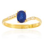 A SAPPHIRE AND DIAMOND RING in 14ct yellow gold, set with an oval cut sapphire between eight round