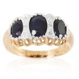 A SAPPHIRE AND DIAMOND DRESS RING in yellow gold, set with three oval cut sapphires and six round