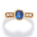 SAPPHIRE AND DIAMOND RING in 18ct yellow gold, set with an oval cut sapphire and round cut