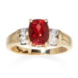 A RED AND WHITE STONE RING in 9ct yellow gold, jewelled with an oval cut red stone between four