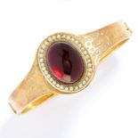 ANTIQUE GARNET AND PEARL BANGLE in high carat yellow gold, comprising a cabochon garnet in a