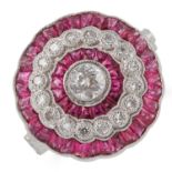 RUBY AND DIAMOND TARGET RING, set with a central old cut diamond, calibre cut rubies and round cut