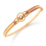 RUBY AND DIAMOND BANGLE set with two round cut rubies and a diamond in twisted gold motif, 6cm inner