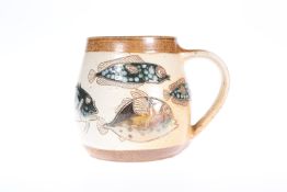 MICHAEL AND JOANNE MOSSE FOR LLANBRYNMAIR POTTERY, A SALT-GLAZED STONEWARE MUG DECORATED WITH FISH