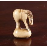 A JAPANESE IVORY NETSUKE OF A GRAZING HORSE