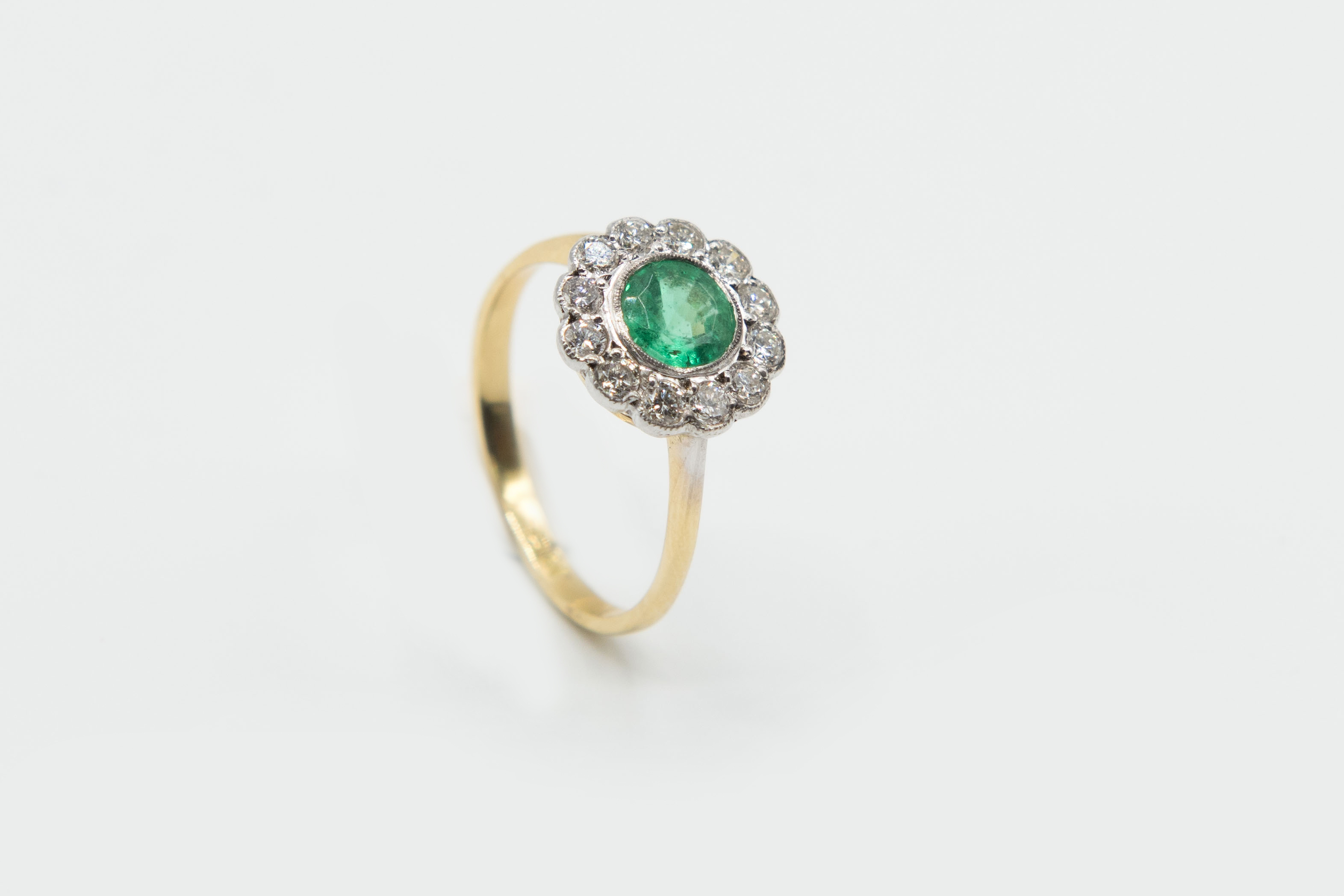 AN EMERALD AND DIAMOND CLUSTER RING