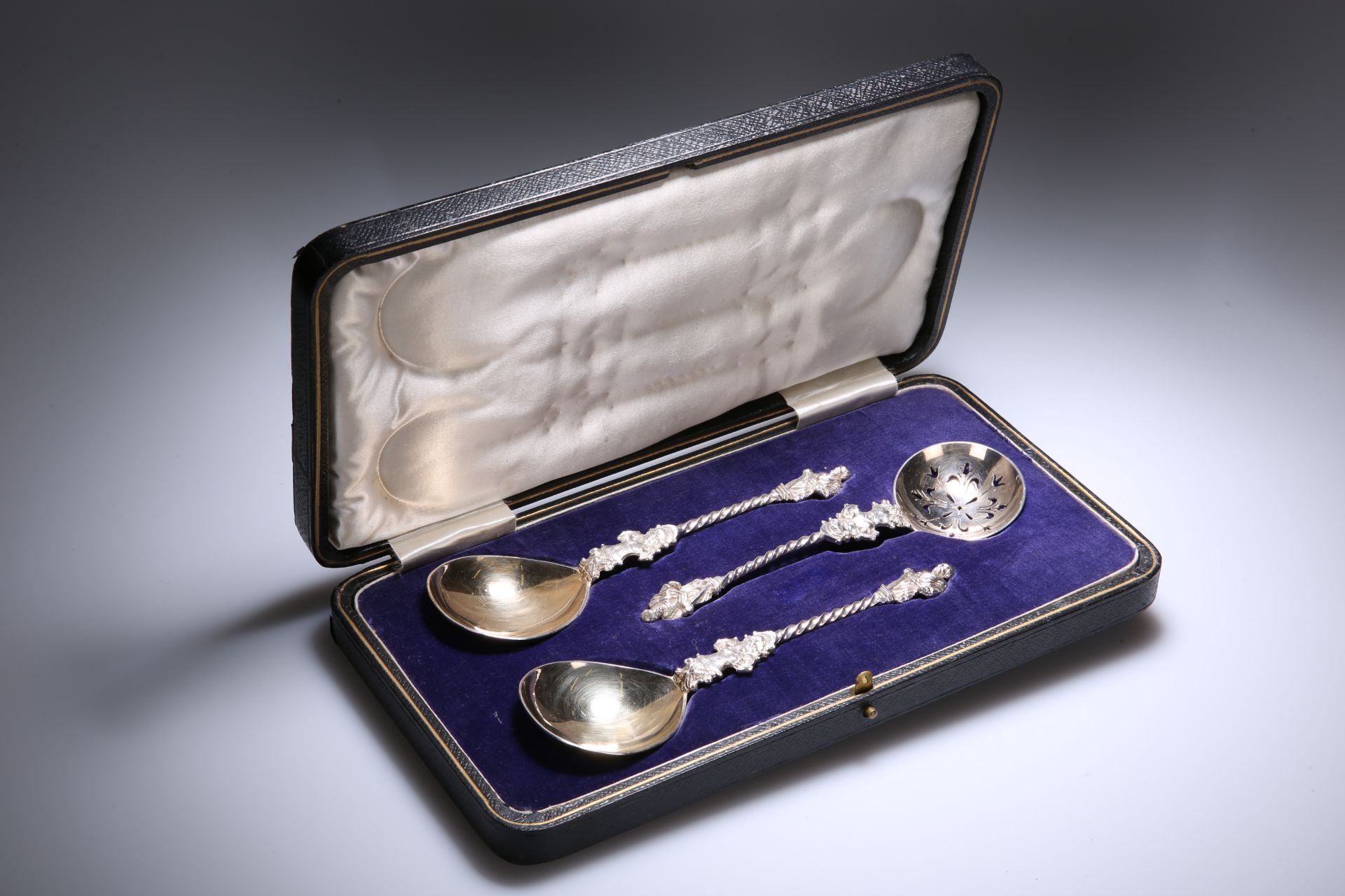AN EDWARDIAN CASED SET OF SILVER-PLATED APOSTLE FRUIT SPOONS AND A SUGAR SIFTING SPOON