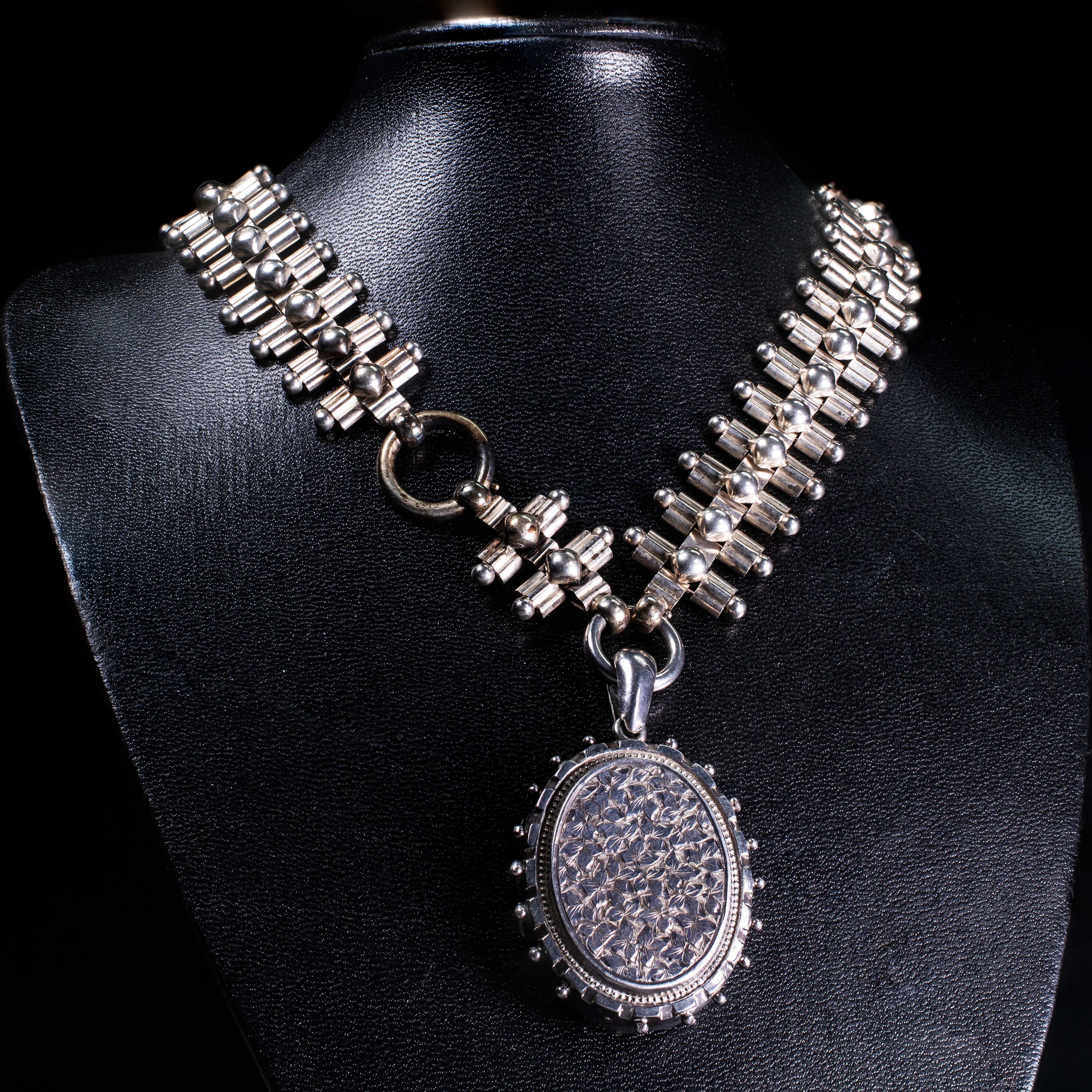 A VICTORIAN SILVER LOCKET SUSPENDED FROM A FANCY LINK COLLAR