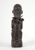 Sitzende Figur mit auf dem Rücken gefesselten ArmenUm den Hals drei Säckchen gebunden. Afrika. Holz,