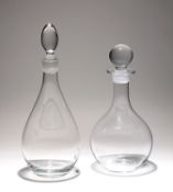 Zwei KaraffenBauchige Gefäßkörper, Kugel- und spitzkugeliger Stöpsel. Farbl. Glas. H 28 cm, 33 cm.