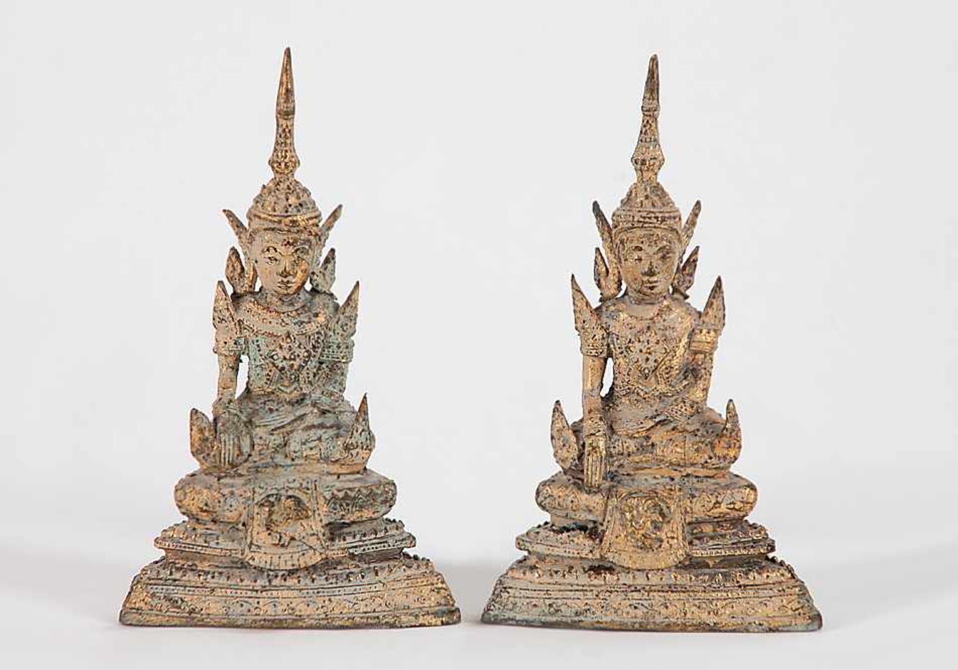 Zwei sitzende BuddhafigurenThailand. Hellgrau patiniertes Metall, Vergoldung. H 16,5 cm.€ 15