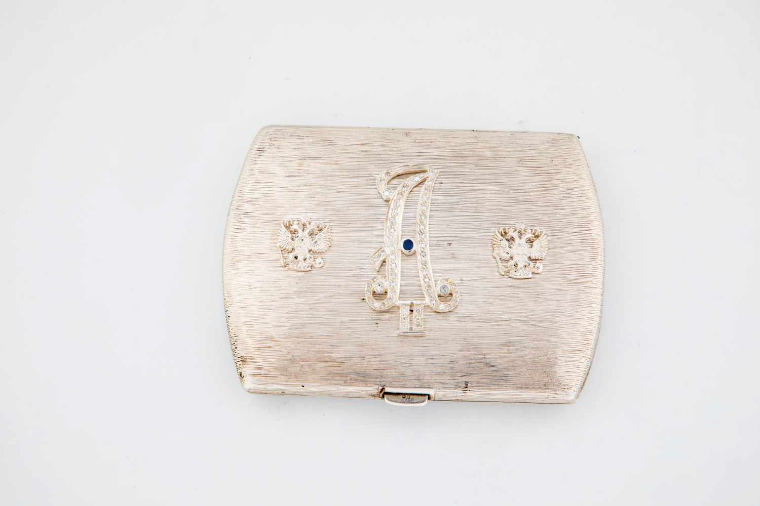 A silver case with diamonds and sapphire. 20th century. Both sides with engraved decor.Lid with