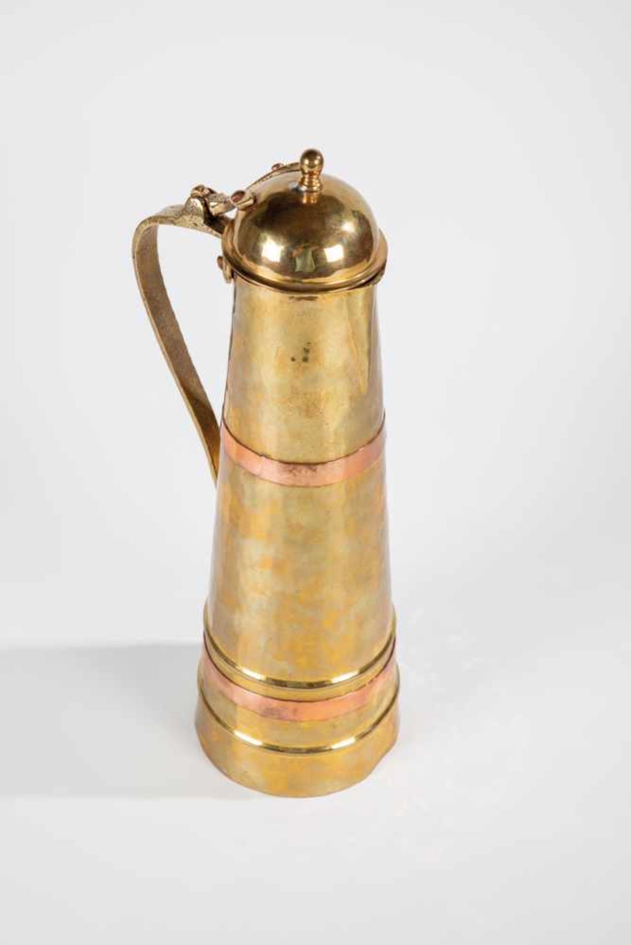 A brass and copper jug. Russia, circa 1930. Hammered decor. Two copper overlays. Bottomwith