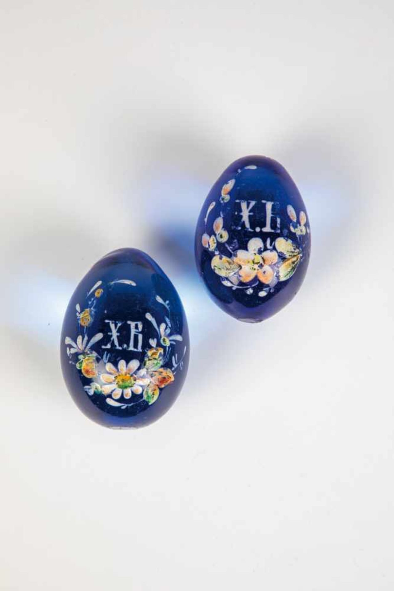 Two blue glass eggs. Russia, 20th century. Decorated with enamel painting. Slightlychipped. 6 - 7 cm