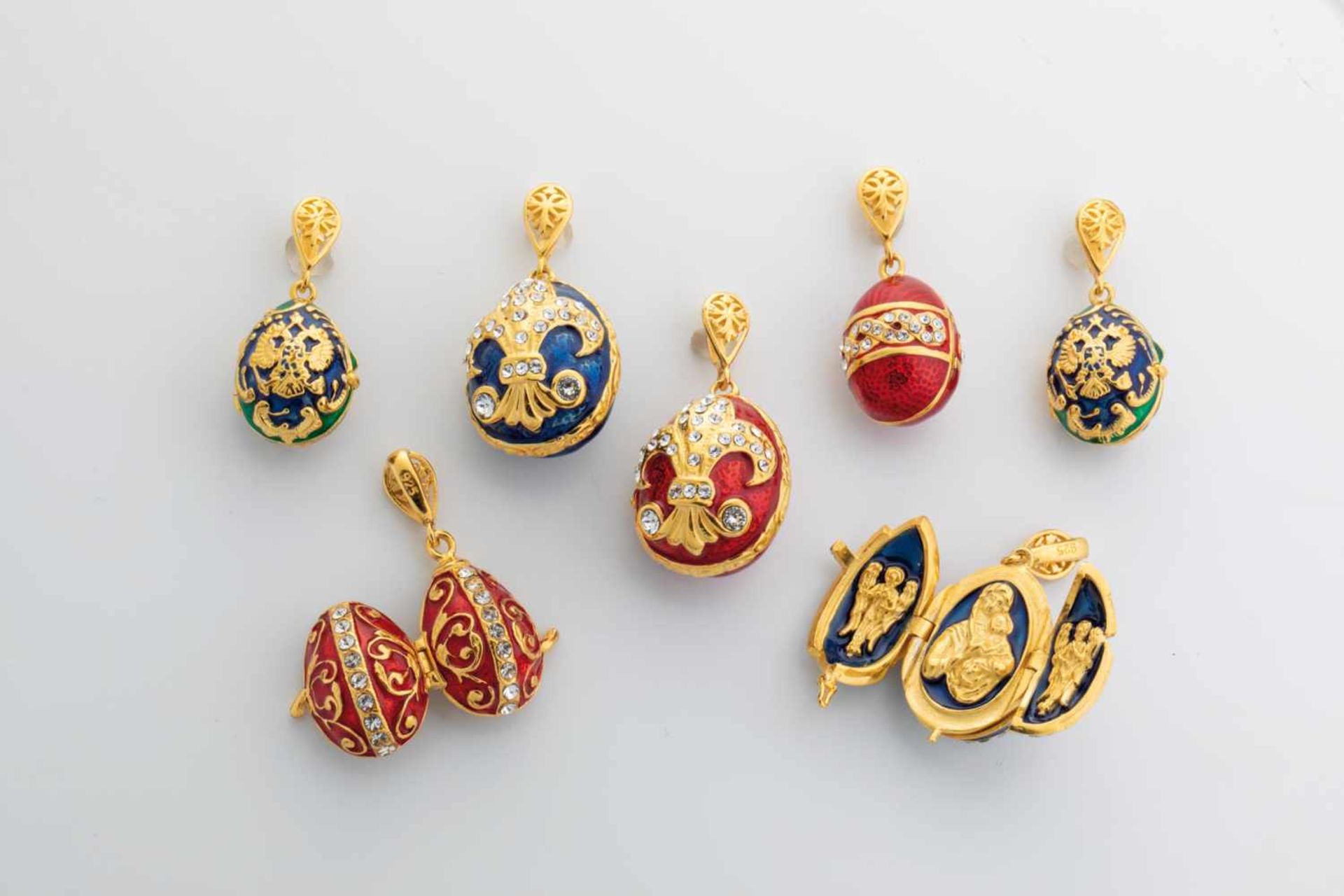 Seven silver-gilt and enamel egg-pendants. Modern. Ovoid body decorated with translucidenamel.