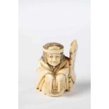 Netsuke. Japan, Meiji period, 19th century. Squatting figure with two panels. Ivorycarved. 4.5 cm