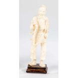 Fisher. China, 19th century. Standing man with stick, basket and fish. Ivory on a woodbase. 15 cm