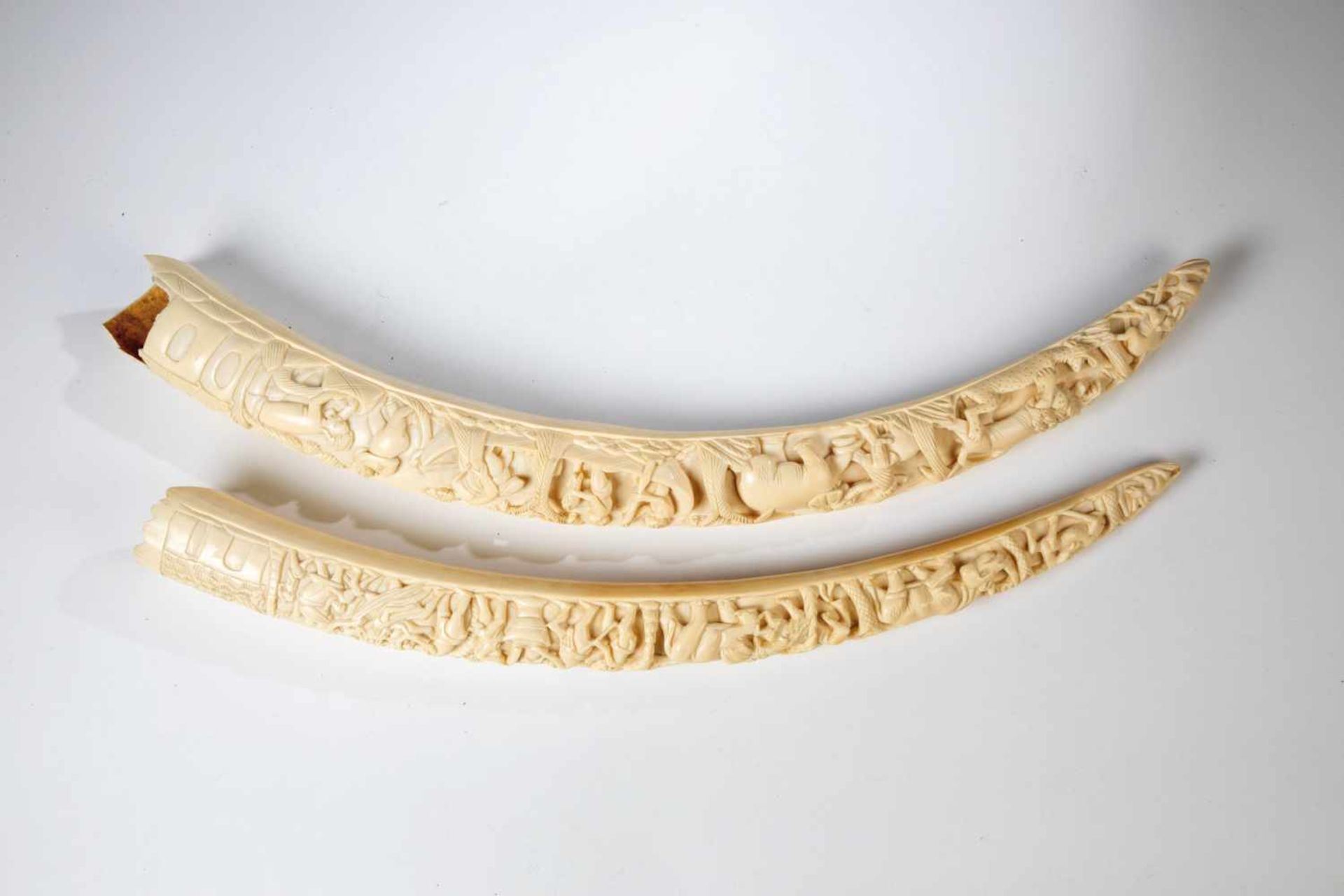 Two tusks. Africa, around 1920. Front relief carving depicting animals and humans. Ivory.Minimum.