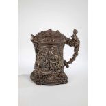 A large plated tin tankard with bacchanal. 19th century. On four feet. Stand with fourmascarons