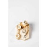 Netsuke. Japan, Meiji period, 19th century. Calligraphy with brush. Ivory carved. Signedon the