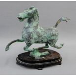 Verdigris patinated metal figure of a Tang style horse on shaped hardwood base, 20cm high