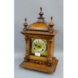 Oak cased mantle clock with urn finials to top above a gilt metal dial with silvered chapter ring