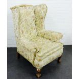 Floral upholstered wing back armchair on claw and ball feet, 105 x 63cm