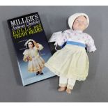 Early 20th century French bisque head doll in later clothes, together with a Millers Antiques Checks