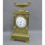 Brass cased mantle clock with a twin handled urn finial over a circular enamel dial with Roman