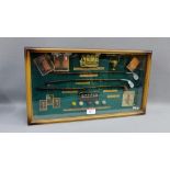 Showcase containing a collection of miniature golfing clubs and golf balls etc., 54cm long