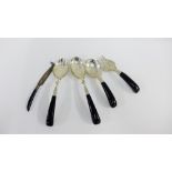 A collection of Eastern white metal and faux ebony handled serving spoons and forks together with