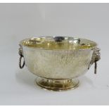 Arts & Crafts hammered silver bowl with lion mask ring handles to side and on circular pedestal