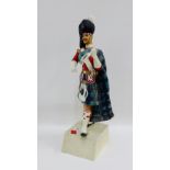 Painted resin figure of a Highland Piper on a painted wooden base, 56cm high