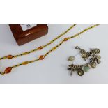 Silver charm bracelet and a strand of amber coloured glass beads (2)