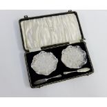 Cased set containing a pair of cut glass butter dishes with Sheffield silver knives, cased