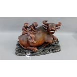 Eastern carved hardwood water buffalo and figures on a shaped hardwood stand, 33cm long