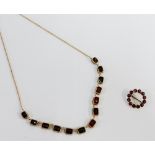 Early 20th century circular garnet brooch and a yellow metal and gemset necklace (2)